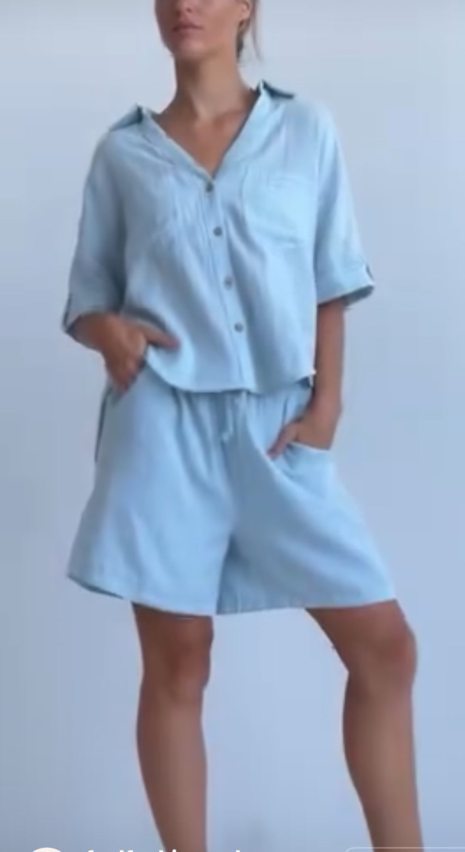 Person wearing a light blue outfit with a shirt and shorts on a plain background