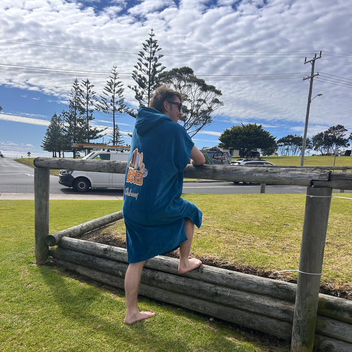 Person in a blue shirt standing near a wooden fence with a scenic background