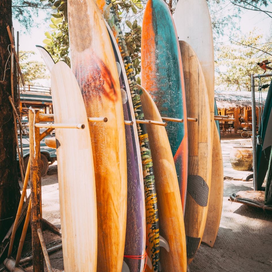 Colorful surfboards leaning against a rack outdoors with trees in the background
