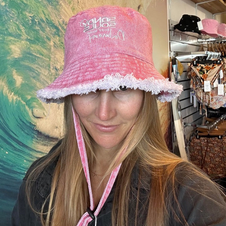 Person wearing a pink bucket hat with white trim in a store setting