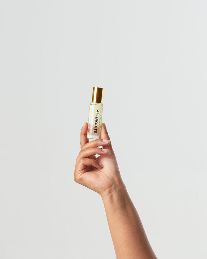 Hand holding a small bottle labeled 'Aromatique' against a light gray background