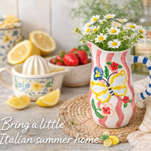 Butterfly-patterned ceramic jug with lemon slices and flowers in a kitchen setting.