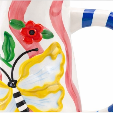 Ceramic jug with butterfly design and striped handle on a white background