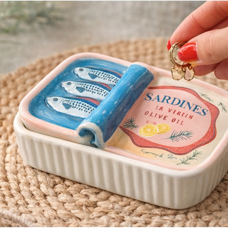 Small decorative container with a lid featuring a design of sardines, used as a jewelry holder.