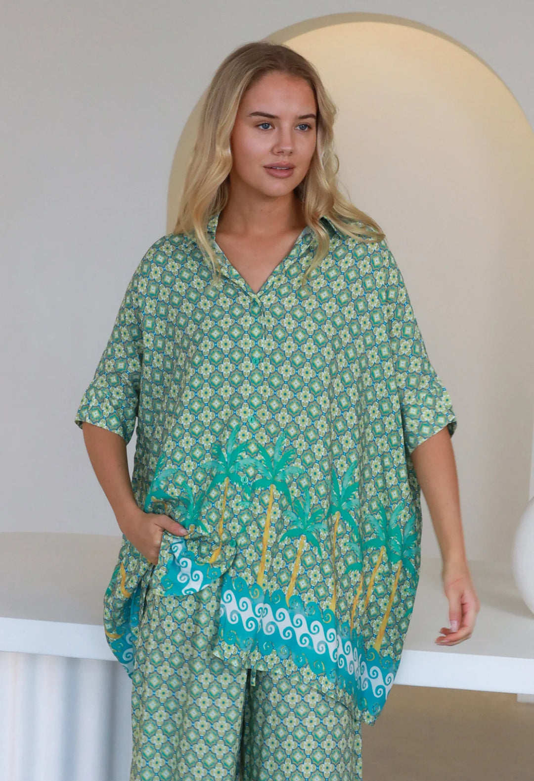 Woman wearing a green patterned outfit with a neutral background
