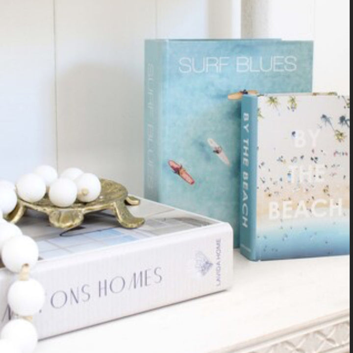 Decorative books on a shelf with a decorative bowl and white ornaments.