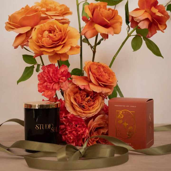 Decorative setup with orange flowers, a red box, and a black container on a surface.