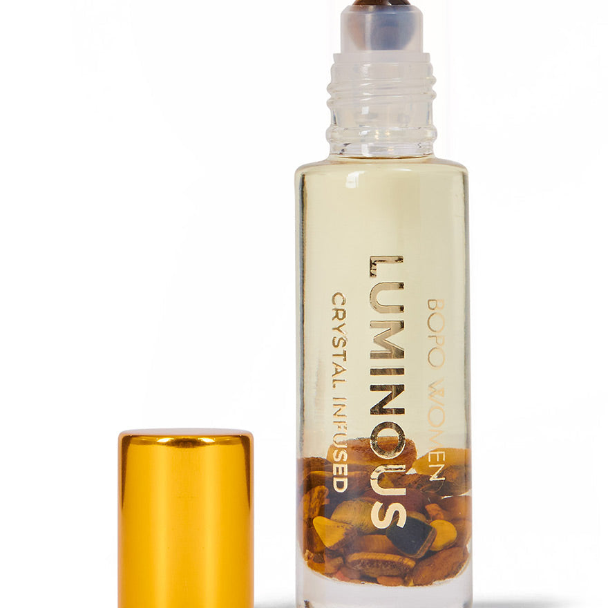 Luminous crystal-infused roller bottle with gold cap on a white background