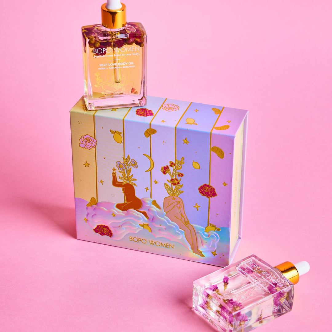 Two bottles of perfume with decorative boxes on a pink background