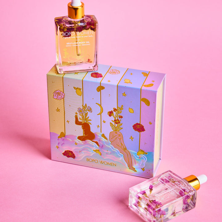 Two bottles of perfume with decorative boxes on a pink background