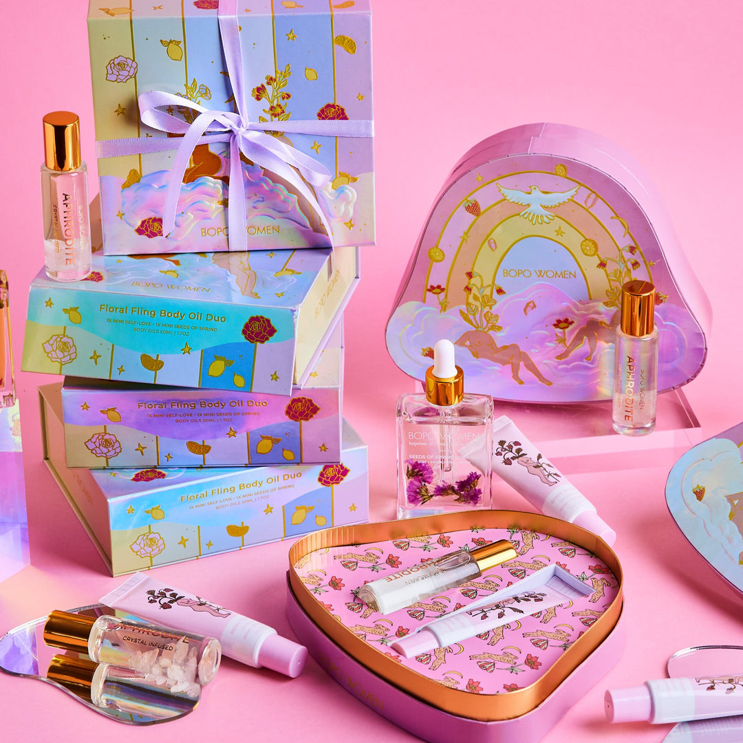 Cosmetic set with heart-shaped mirror, bottles, and boxes on a pink background