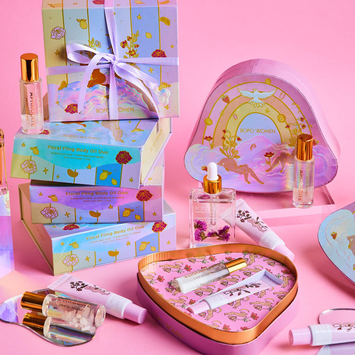 Cosmetic set with heart-shaped mirror, bottles, and boxes on a pink background