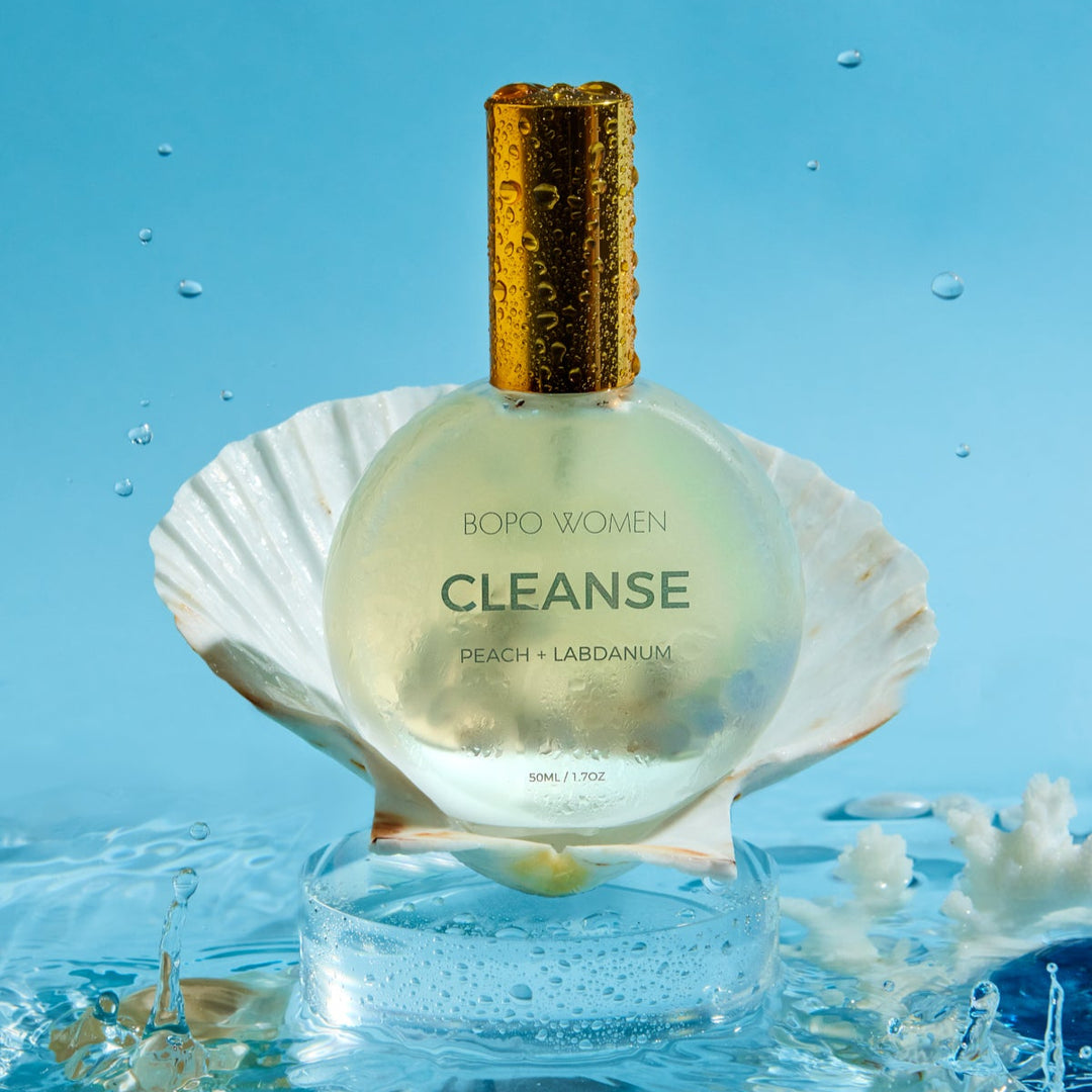 Bottle labeled 'CLEANSE' on a shell with water droplets and blue background
