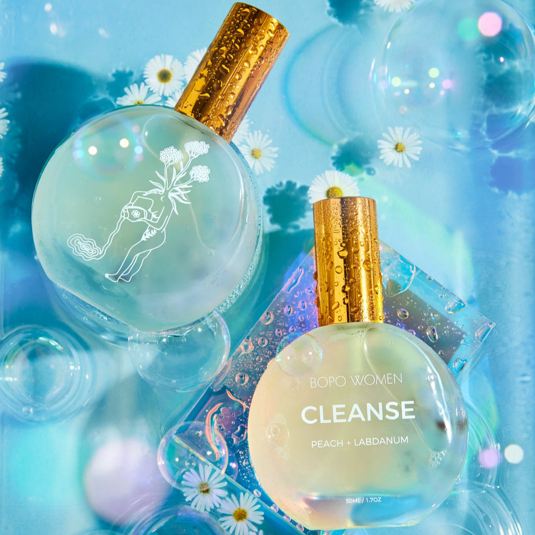 Two perfume bottles labeled 'Cleanse' with floral and bubble design on a blue background