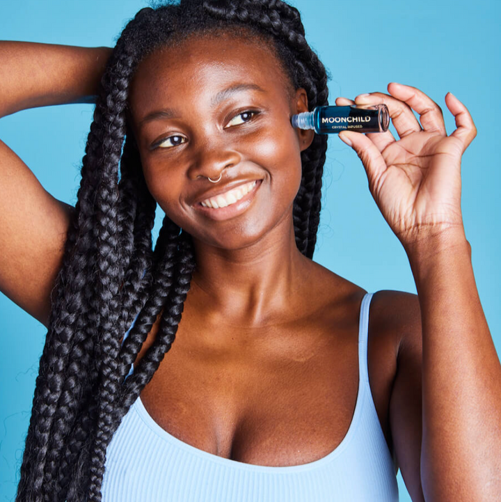 Woman holding a bottle of MoxiNchild product against a blue background