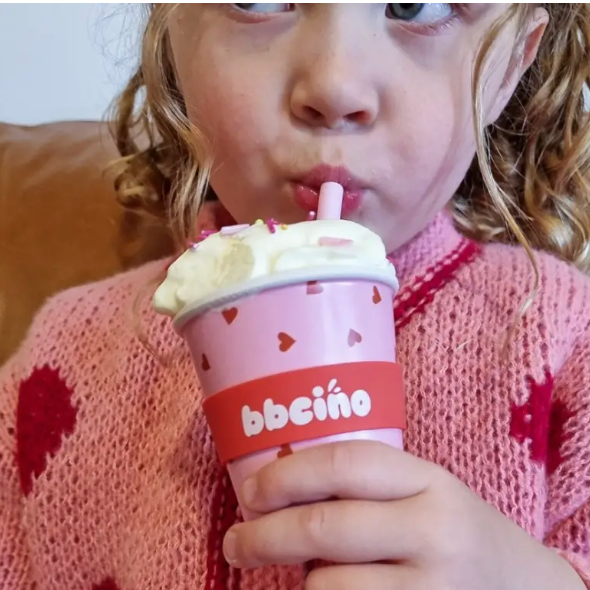 Child drinking from a pink bceño cup with a straw