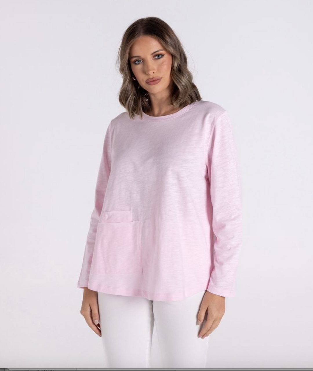 Woman wearing a light pink sweater and white pants on a white background