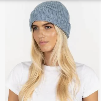 Woman wearing a blue knitted beanie and white t-shirt on a white background